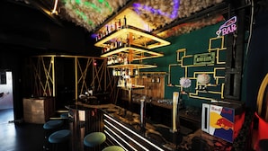 Una zona de bar con un letrero de neón, el logotipo de Red Bull y un letrero que dice 'Nunca Duerme'.