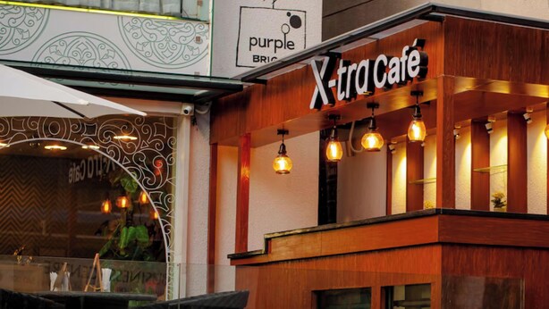Un edificio con un letrero que dice "Xtra Café" y otro letrero que anuncia "Purple BRIO".