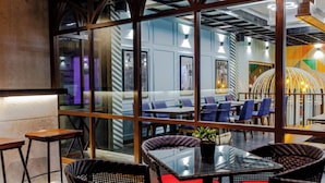 Un restaurante moderno con divisiones de vidrio, asientos azules y una combinación de mesas y sillas.