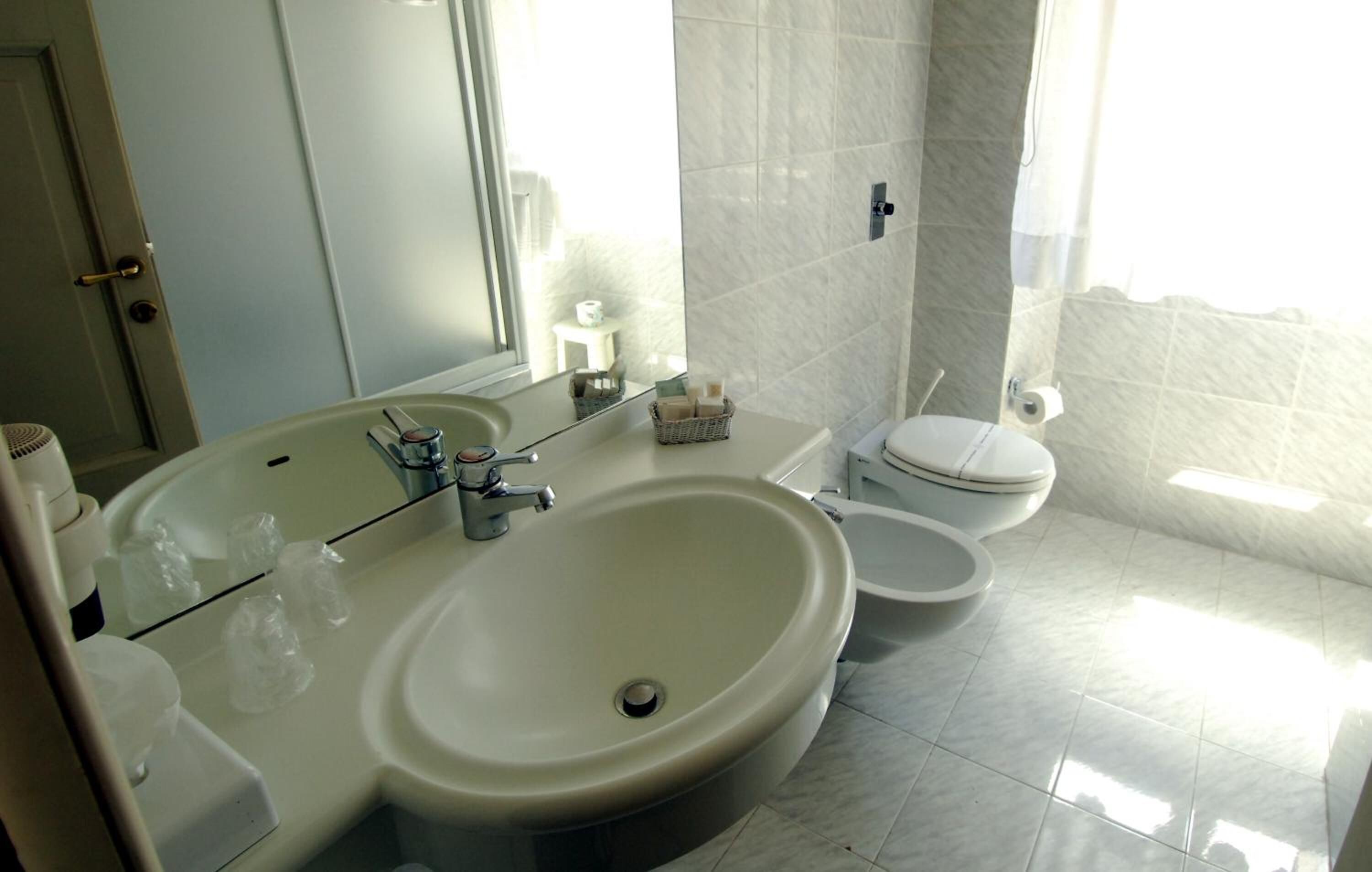 A bathroom with a large sink, toilet, and a mirror.