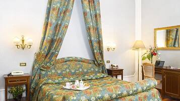 Ein Schlafzimmer mit Baldachinbett, Nachttischen, Schreibtisch, Stuhl und Spiegel.