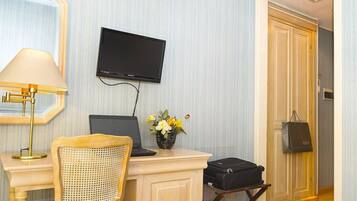 Una habitación de hotel con escritorio, silla, televisor y una pequeña mesa con un florero.