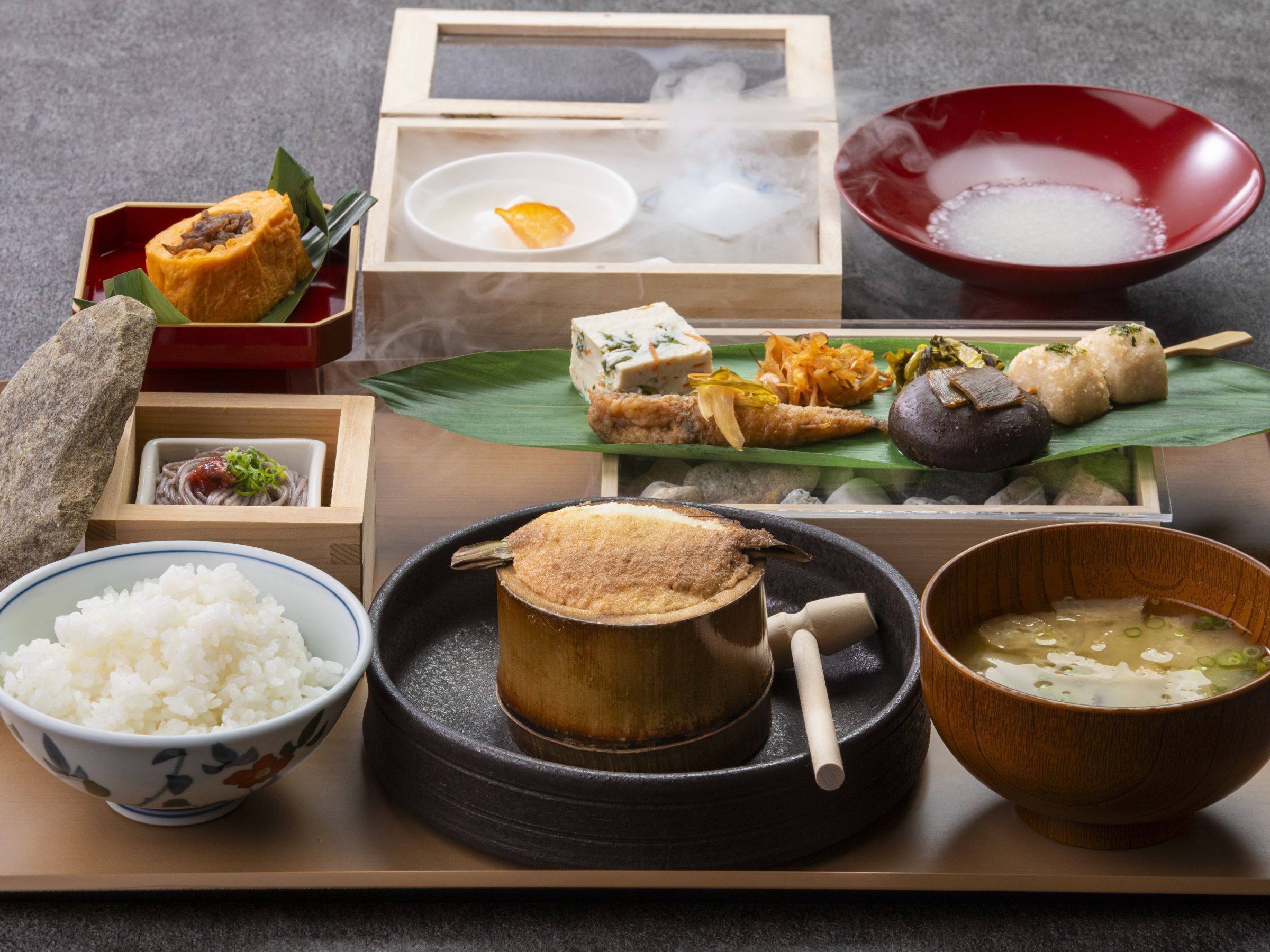 A traditional Japanese meal setup with various dishes including rice, soup, and pickled vegetables.
