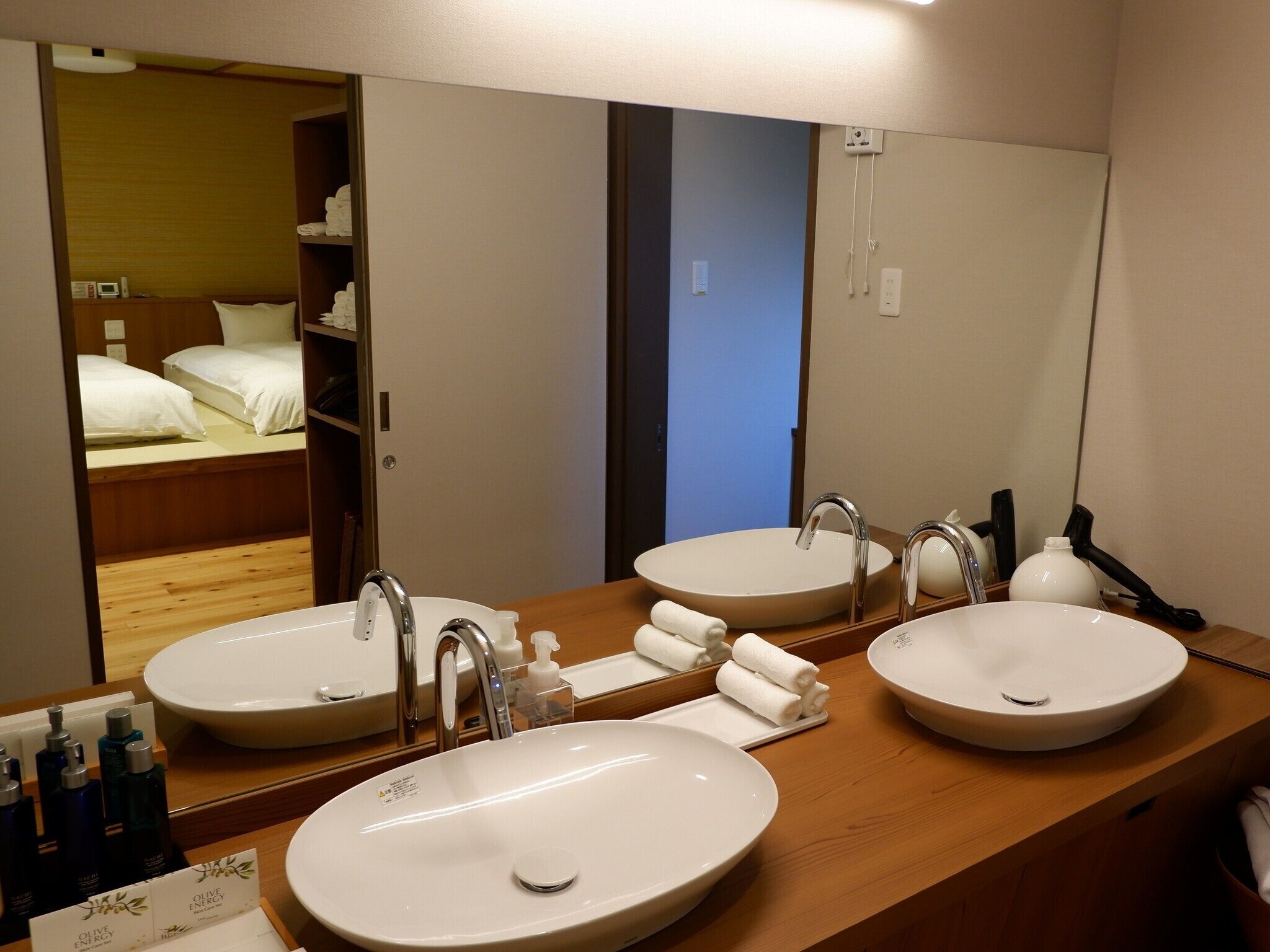 A hotel bathroom with two sinks, a mirror, and a wooden vanity.