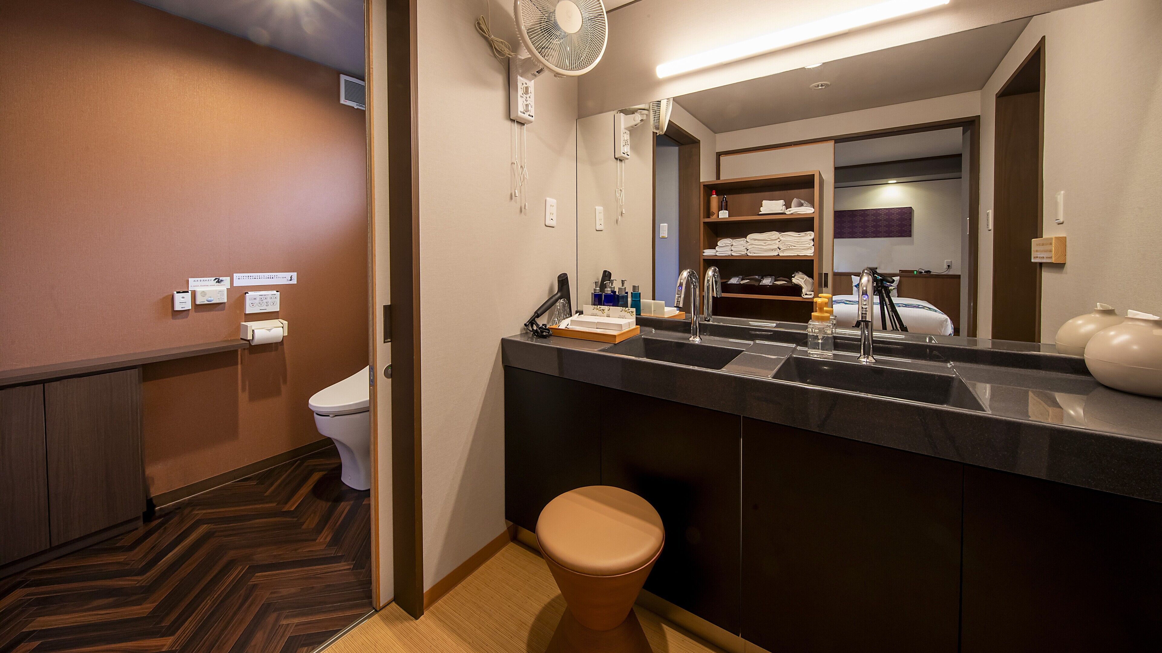 Une salle de bain d’hôtel au design moderne, comprenant un lavabo, un miroir et des toilettes.
