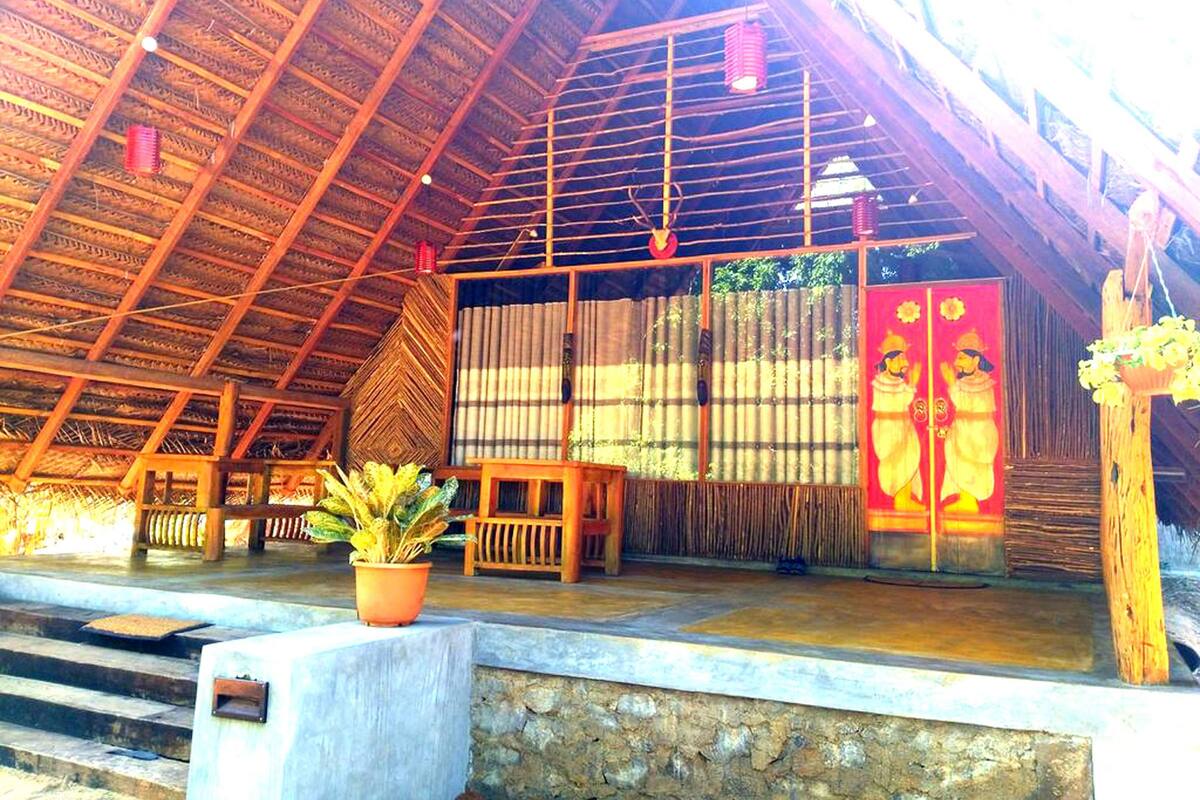 Una estructura de madera tradicional con techo de paja, pared de piedra y banco de madera.