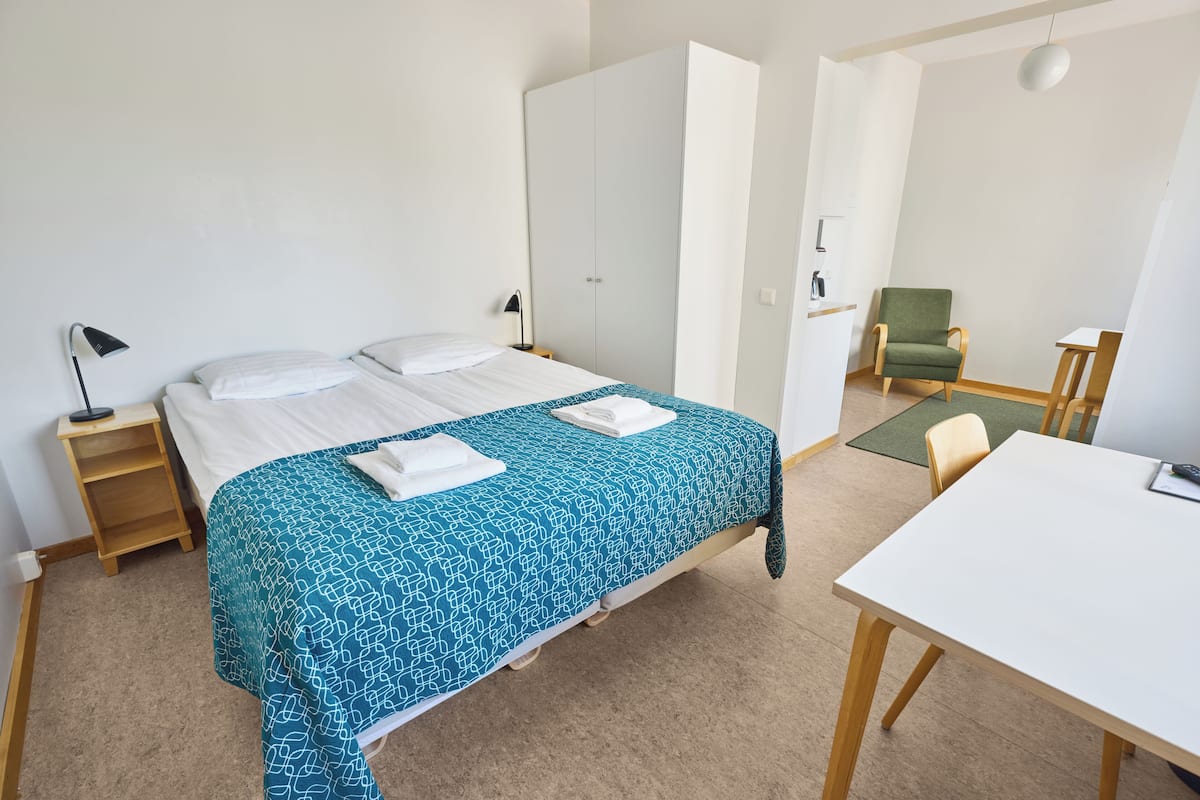 A neatly arranged bedroom with a bed, bedside table, and a desk with a chair.