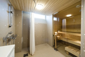 A modern bathroom with a shower, a glass-enclosed sauna area, and wooden benches. - Töölö Towers (Helsinki)