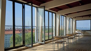 A balcony with large windows, wooden tables, and chairs. - Töölö Towers (Helsinki)