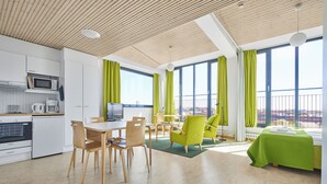 A modern kitchen with white cabinets and appliances, a dining area with wooden chairs and a table, and a balcony with green curtains. - Töölö Towers (Helsinki)