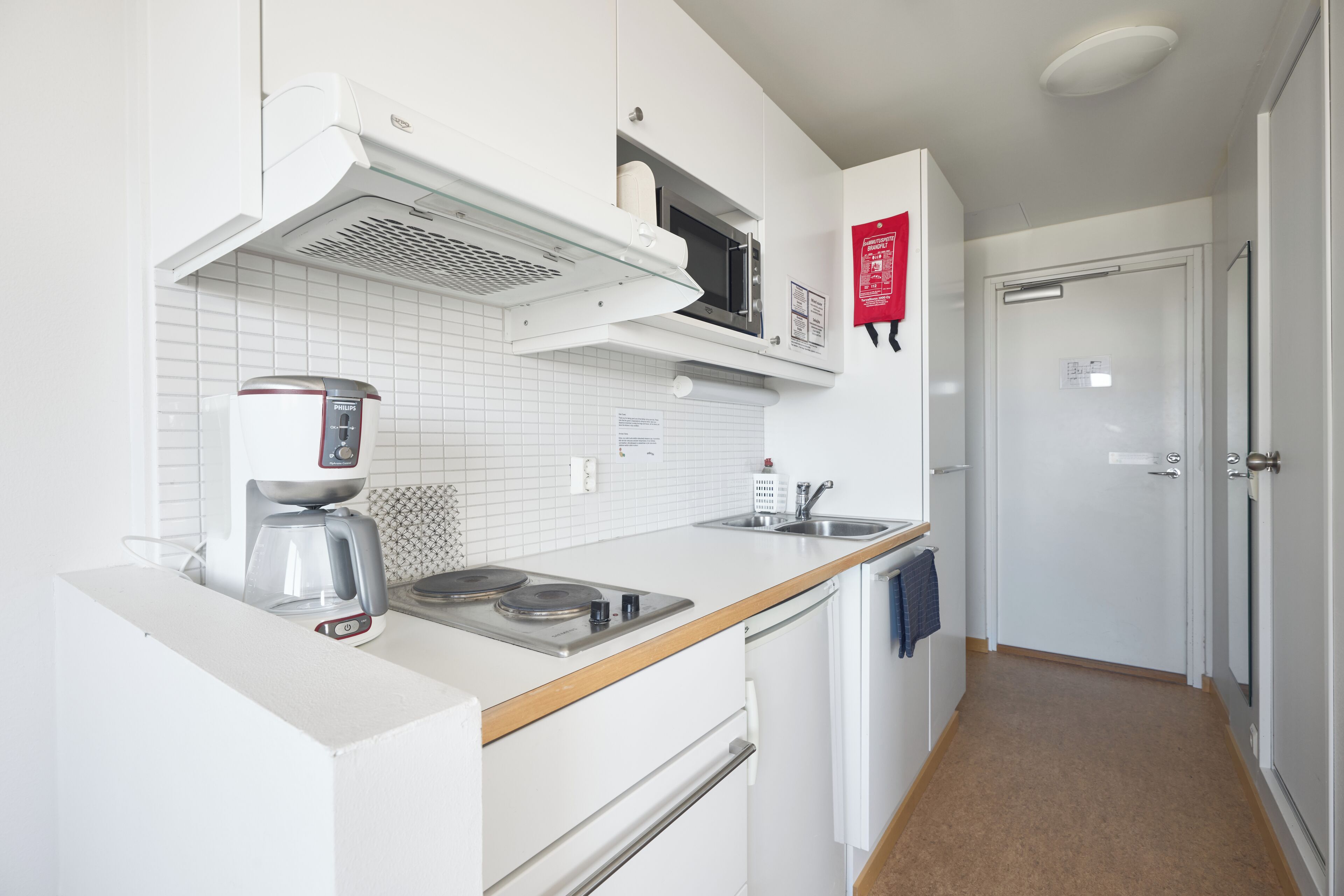 A modern kitchen with white cabinetry, a built-in microwave, a coffee maker, and a sink.