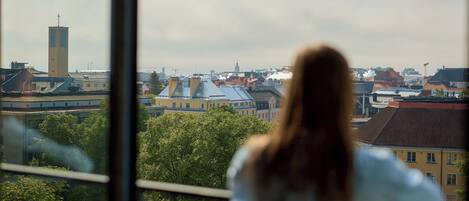 A view from a window overlooking a cityscape with buildings and trees.