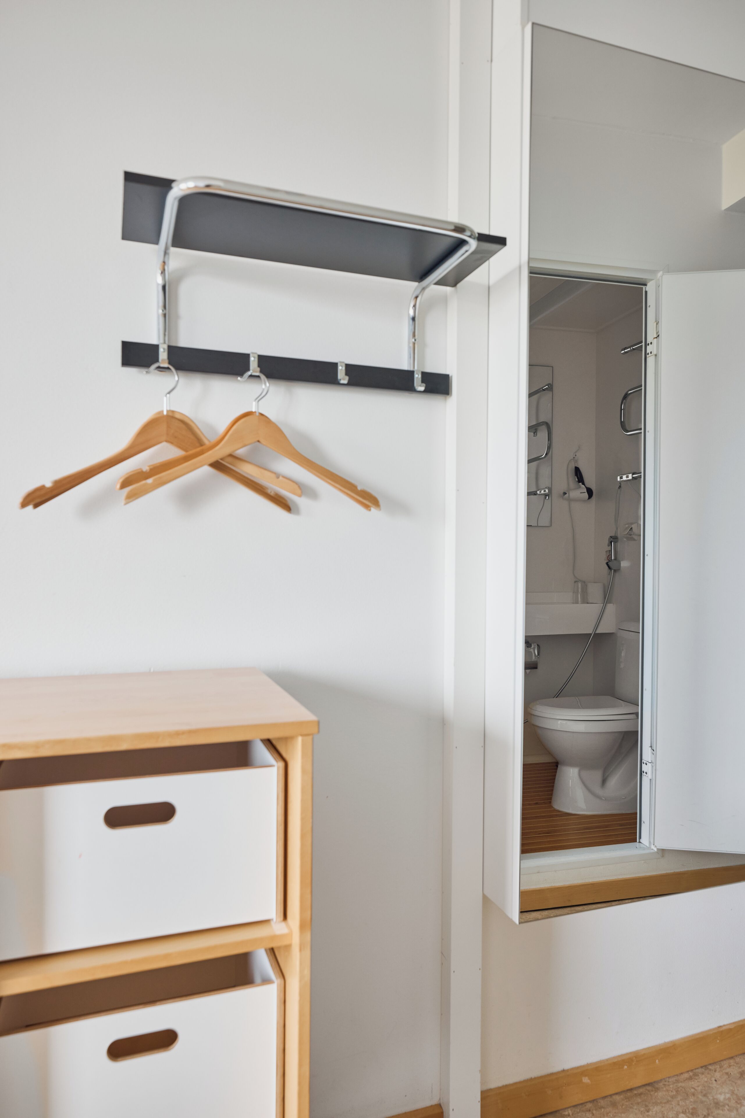 Un baño con ducha, inodoro y un mueble de madera con cajones.