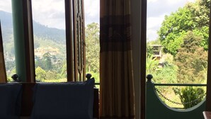 Un dormitorio con cama, cortinas y vistas a zonas verdes y colinas.