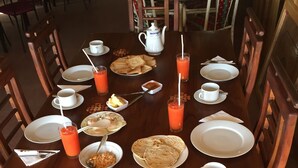 Una mesa de desayuno servida con platos, vasos y diversos alimentos.