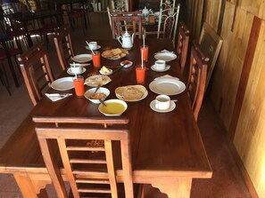A wooden dining table set with plates, bowls, cups, and a pitcher.