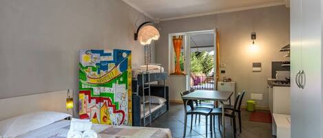 A compact hotel room with a bed, a dining table, and a kitchenette.