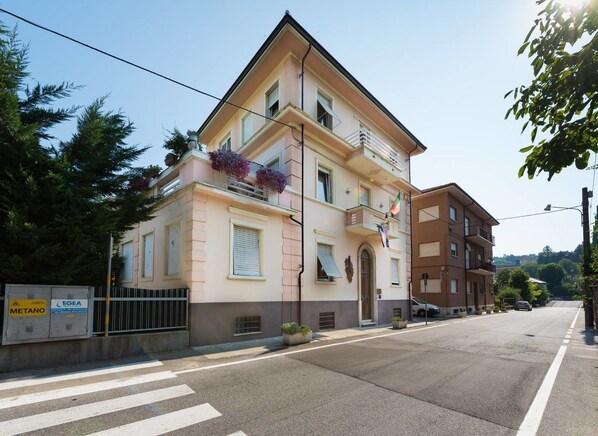 Ein zweistöckiges Gebäude mit Balkon, einer Flagge und Blick auf die Straße.
