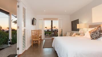 A bedroom with a bed, a nightstand, a lamp, and a view of the outdoors.