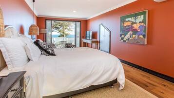 A bedroom with a large bed, a desk, and a painting on the wall.