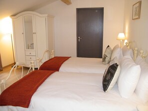 Un dormitorio con dos camas, un armario, una puerta y una lámpara de noche.