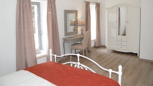 Une chambre à coucher comprenant un lit, un bureau, une chaise, une commode et un lustre.