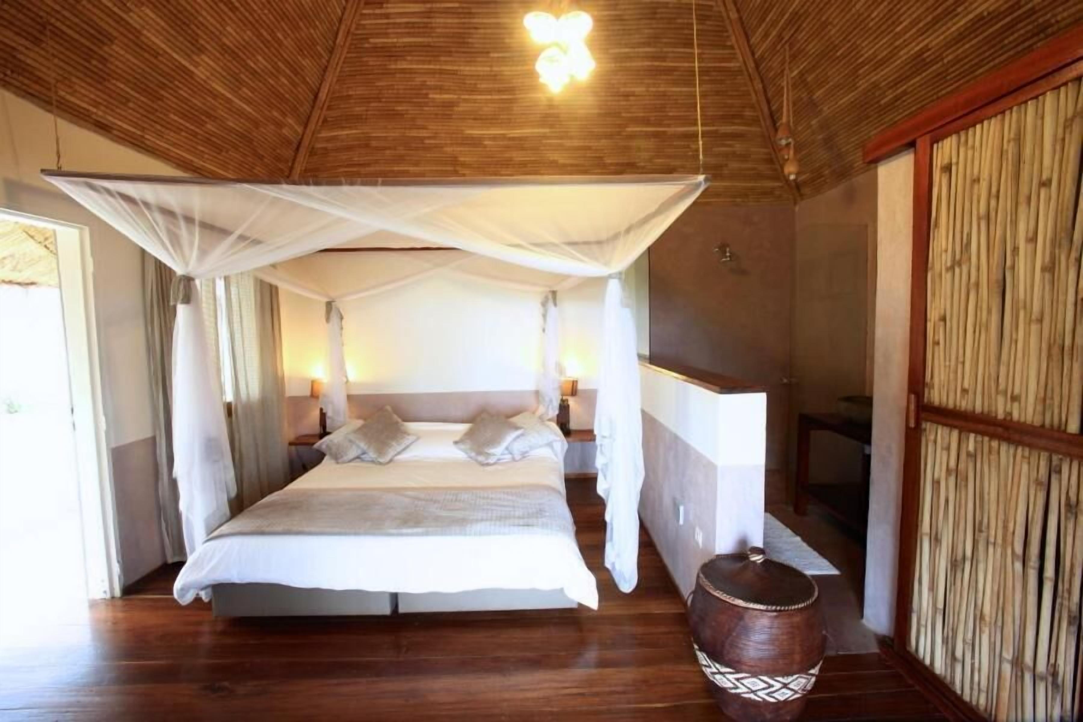 A bedroom with a canopy bed, wooden flooring, and a traditional design.