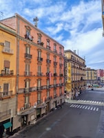 Una veduta di una strada con un hotel su diversi piani, balconi e cielo sereno.