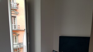 A hotel room with a bed, pillows, and a view of a building through an open window. - Art Street Hotel (Naples)