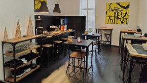 A modern kitchen with a central island, bar stools, and a dining area with tables and chairs. - Art Street Hotel (Naples)