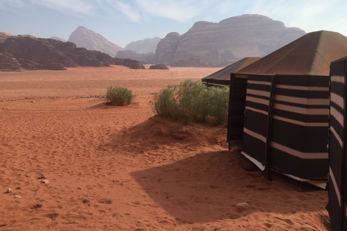 A desert landscape with tents and sparse vegetation.