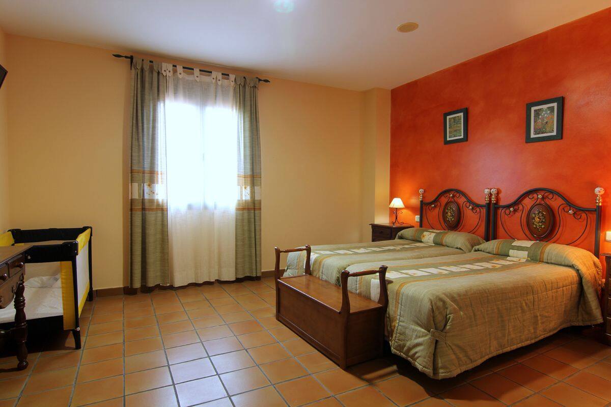 A hotel room with two beds, a desk, and a window with curtains.