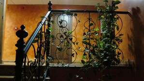 Una escalera con barandilla de hierro forjado, una puerta de madera y una pared con un pequeño cuadro.