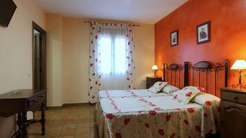 A bedroom with a bed, bedside tables, a nightstand, a dresser, and a window with curtains.