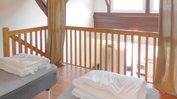 A room with a wooden balcony, a bed with white bedding, and a window with curtains. - Amazing apartment in Ystad with WiFi (Ystad)