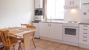 A compact kitchen with a dining table, chairs, a microwave, a stove, and cabinets. - Amazing apartment in Ystad with WiFi (Ystad)