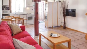 A living room with a red sofa, a wooden table, and a kitchen in the background. - Amazing apartment in Ystad with WiFi (Ystad)