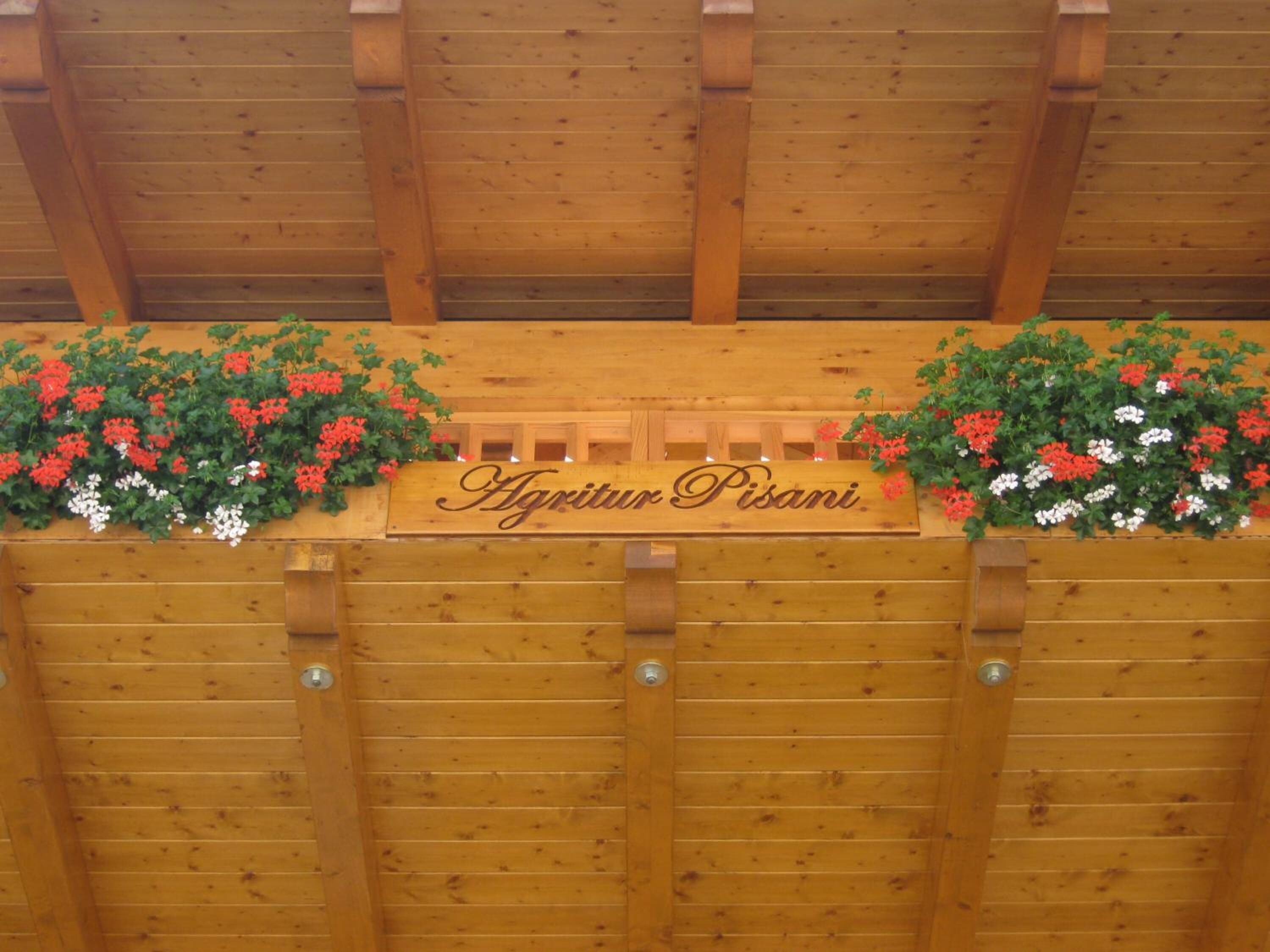 A wooden fence with a sign that reads "Agritur Pisani."