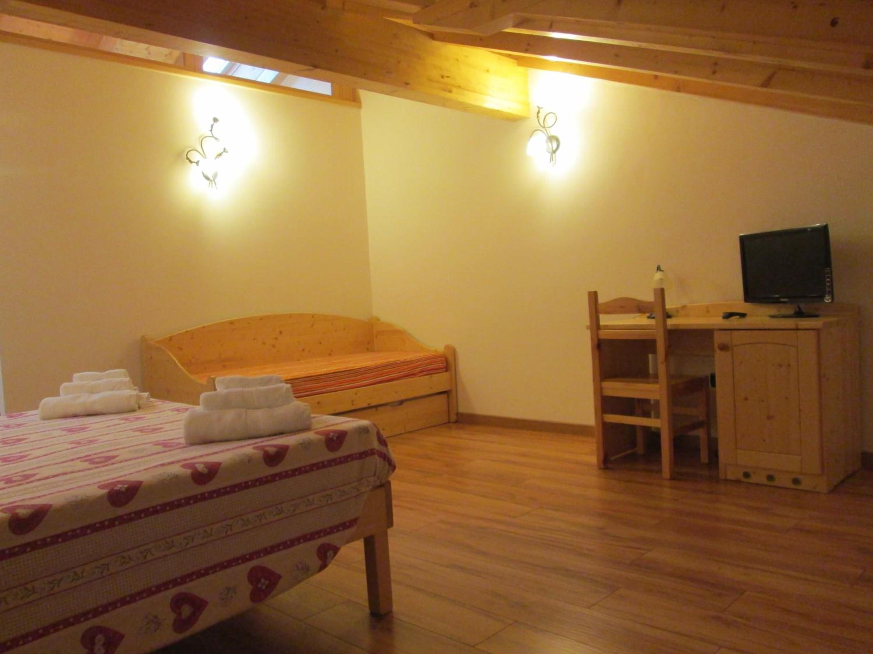Une chambre à coucher avec un lit, un bureau, une télévision et un lit superposé.
