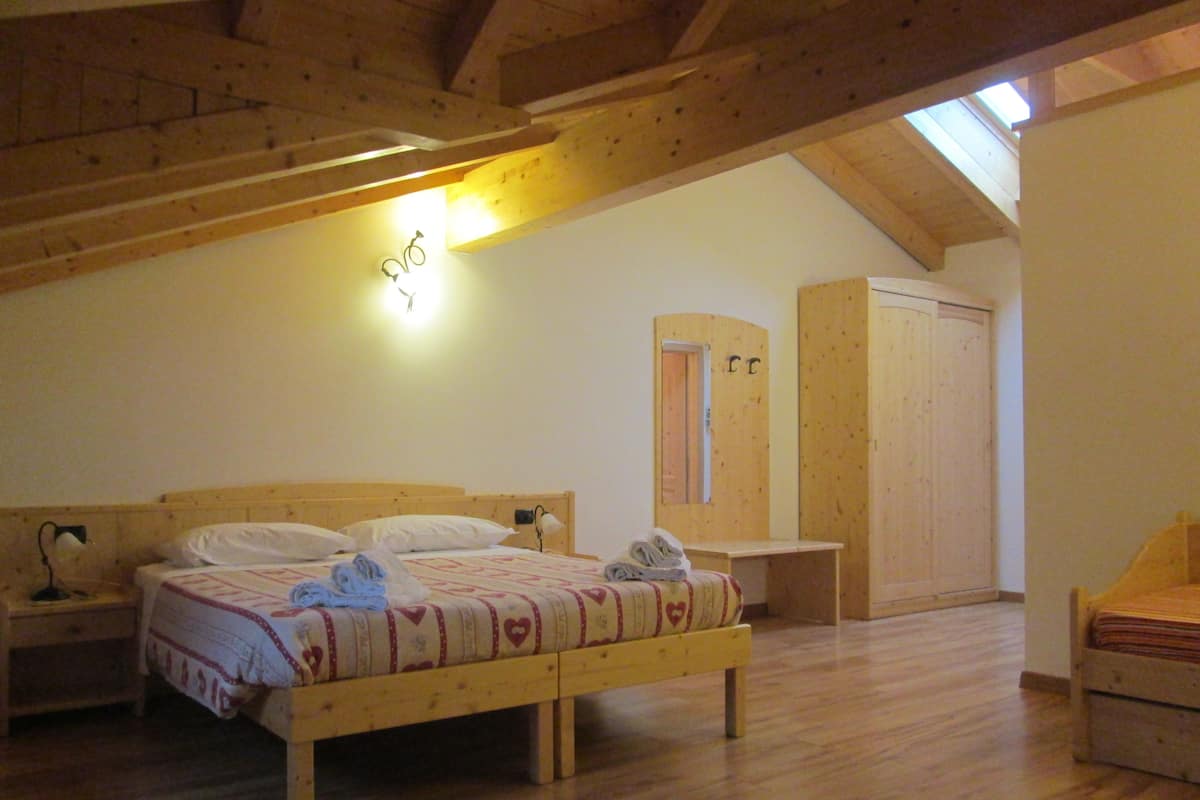 A bedroom with a wooden bed, a nightstand, a desk, and a wardrobe.
