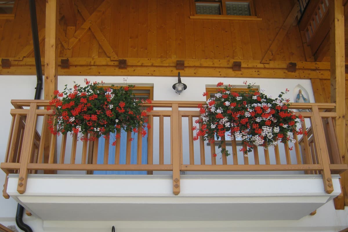 A wooden balcony with flower baskets.