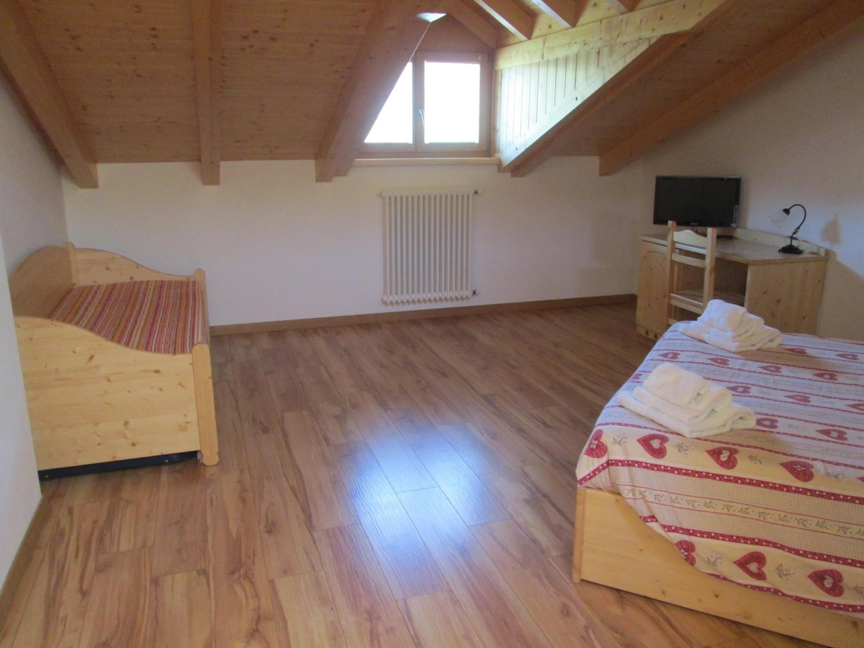 Una habitación con una cama de madera, un escritorio de madera, un radiador y una ventana.