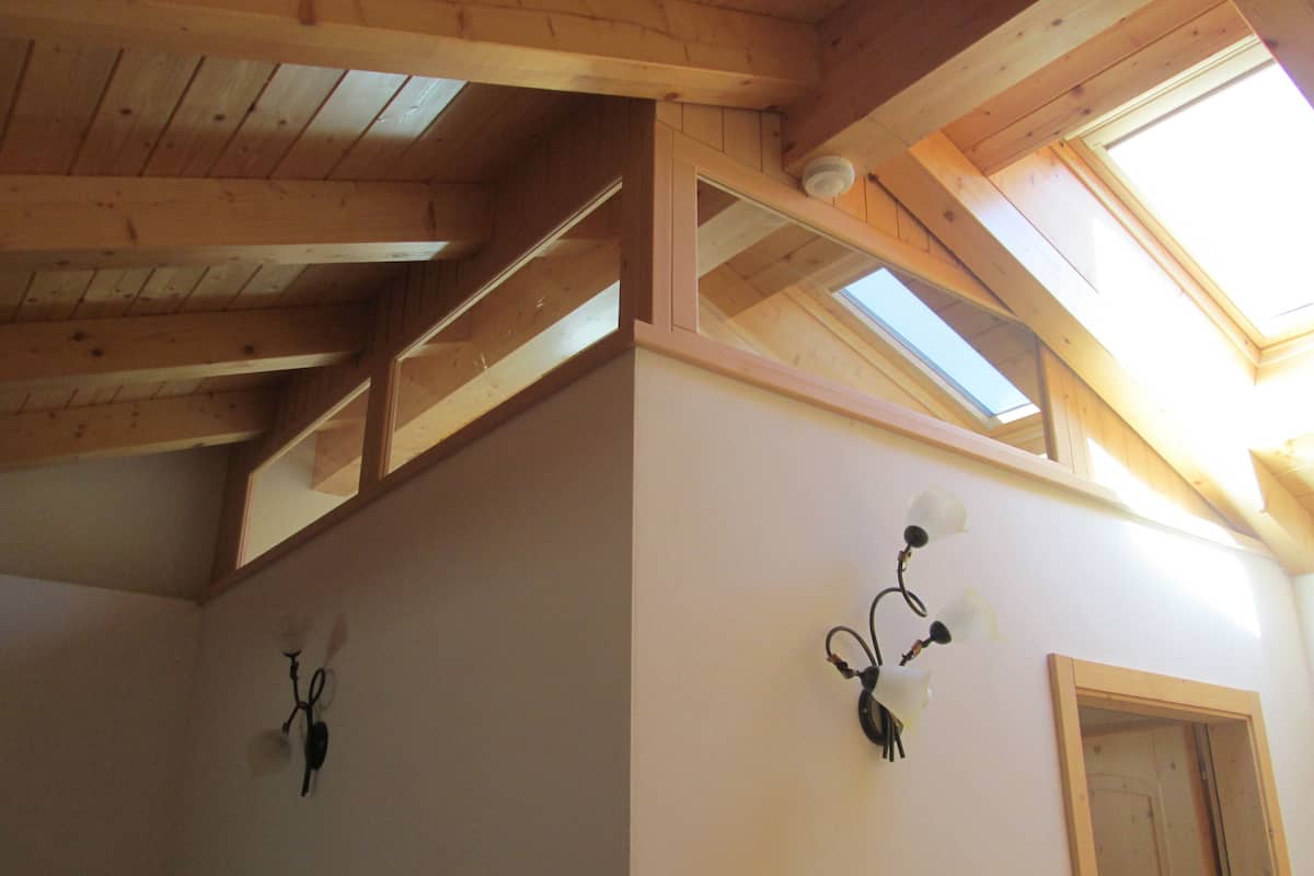 A room with wooden beams, skylights, and wall-mounted light fixtures.