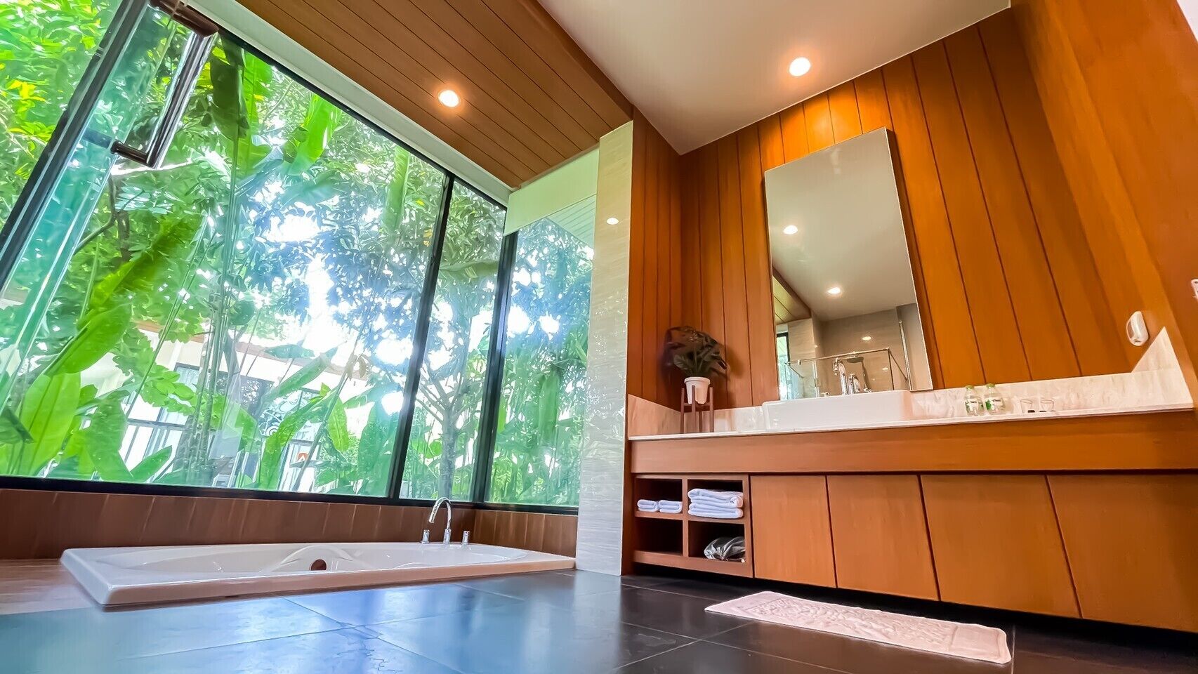 Ein modernes Badezimmer mit großem Fenster, einer Badewanne und einem Waschtisch mit Spiegel.
