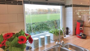A kitchen with a window view of a green field and trees, a stainless steel sink, a red coffee maker, and jars labeled "Coffee" and "Tea". - Lovely home in Baarle-Nassau (Baarle-Nassau)
