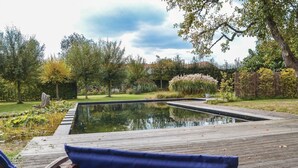A wooden deck with a rectangular pool, surrounded by lush greenery and trees. - Lovely home in Baarle-Nassau (Baarle-Nassau)