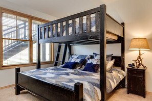 A bunk bed with a ladder, a bedside table with a lamp, and a window with blinds. - Corral 3bd/3ba , Downtown Breckenridge, 3 King Beds, Walk to Ski Lift, Hot Tub (Breckenridge)