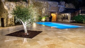 A swimming pool with stone walls and an olive tree in the center. - En Rou Libre (Rou-Marson)