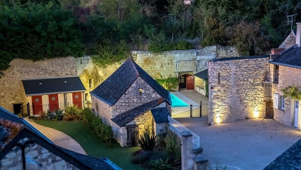 A stone building with a covered outdoor seating area and a small garden. - En Rou Libre (Rou-Marson)