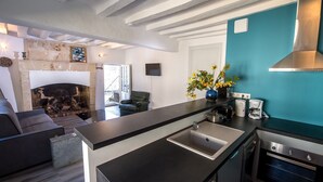 A modern kitchen with a built-in oven, a large island with a sink, and a teal accent wall. - En Rou Libre (Rou-Marson)